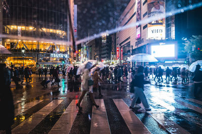 Crowd walking on street during rainy season in city at night