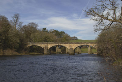 Arch bridge over river against sky