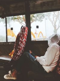 Rear view of man sitting in glass window