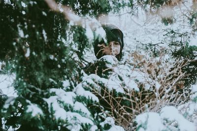 Woman amidst snow covered tree in forest