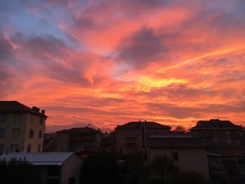 Silhouette houses against orange sky