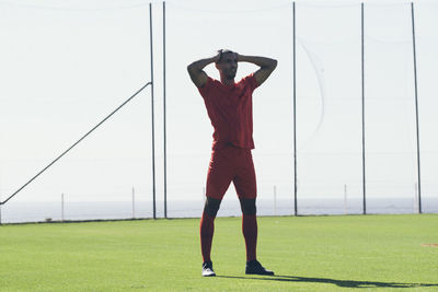 African american male soccer player standing on grass at pitch