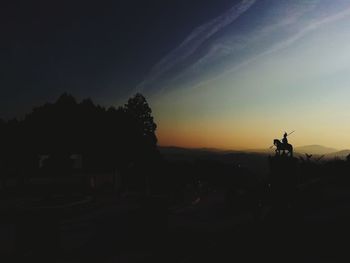 Silhouette statue against sky at sunset