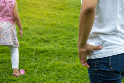 A woman's hand touching the waist while standing waiting for her daughter playing. 