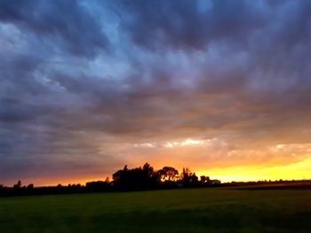 Scenic view of dramatic sky over field during sunset