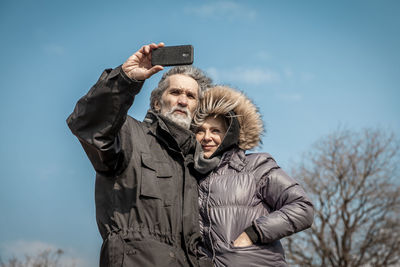 Low angle view of man photographing against sky