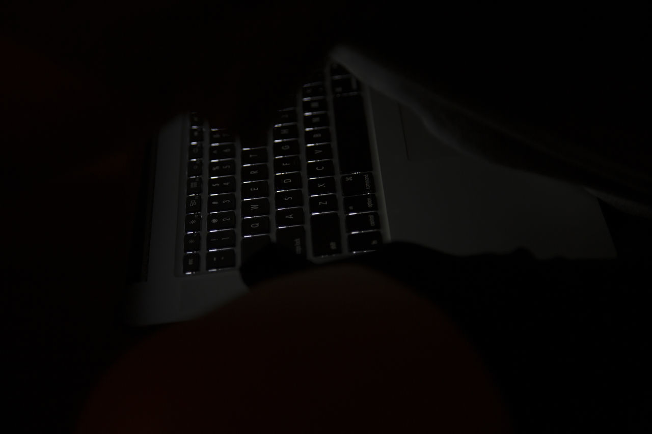 CLOSE-UP OF COMPUTER KEYBOARD IN DARKROOM AT NIGHT