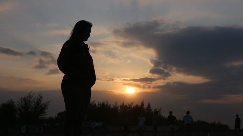Silhouette people standing against sky during sunset