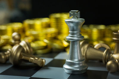 Close-up of chess pieces and coins on board