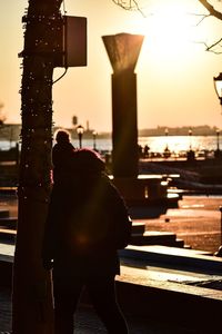 Rear view of silhouette man by sea against sky during sunset