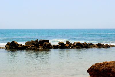 Rocks in sea against clear sky