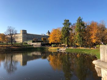 Scenic view of lake by buildings against clear blue sky