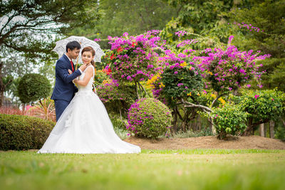 Newlywed couple romancing on grassy field at public park