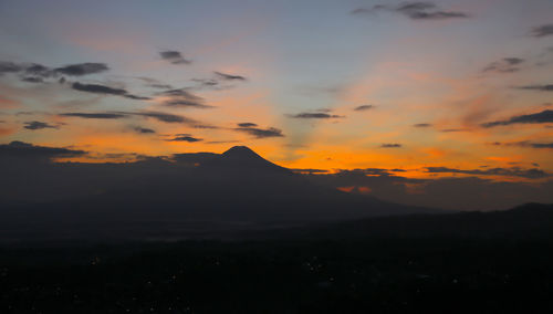 Scenic view of silhouette mountains against orange sky