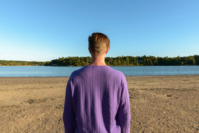 Rear view of man looking at sea against clear sky