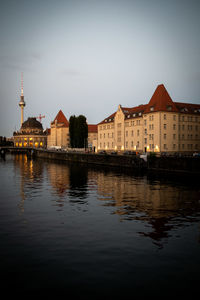 Buildings by river against sky