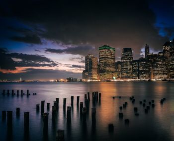 Reflection of illuminated buildings in sea at sunset