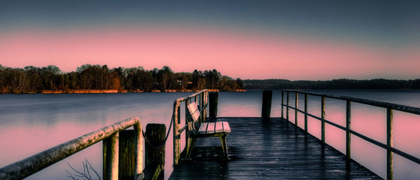 Pier over lake against sky during sunset