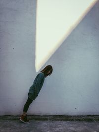 Side view of woman leaning on wall