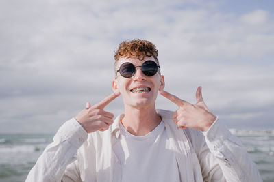 Portrait of smiling woman wearing sunglasses against sky