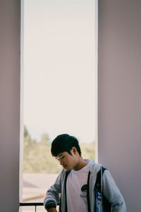 Portrait of young man looking through window