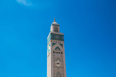 Low angle view of hassan ii mosque tower against blue sky - casablanca, morocco 