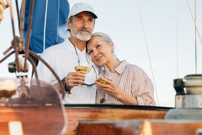 Senior couple holding wineglass standing on boat