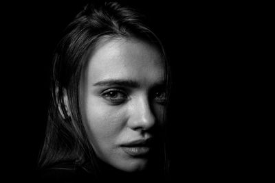 Close-up portrait of young woman over black background