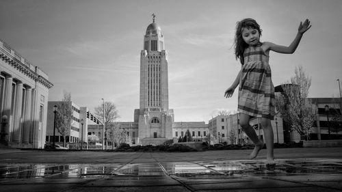 Cute girl playing on wet footpath against sky