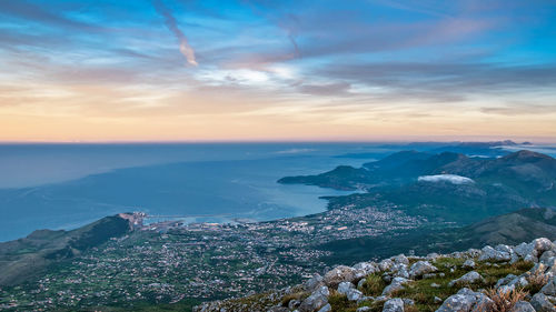 Scenic view of sea by townscape during sunset