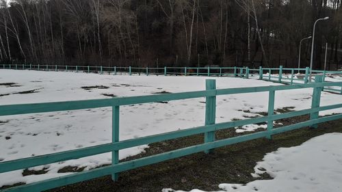 Snow covered field seen through fence