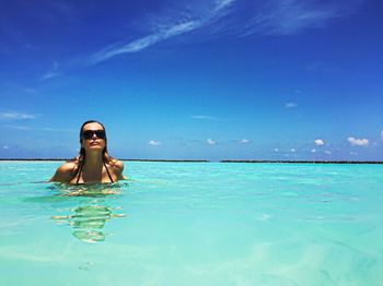 Sensual woman swimming in sea against blue sky