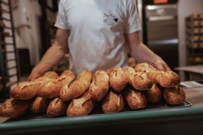 Midsection of man bringing baguettes 