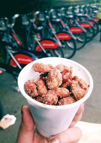 Cropped hand of person holding food in glass outdoors