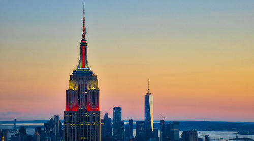 Empire state building and modern towers against clear sky at sunset