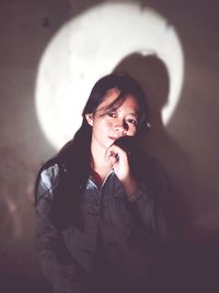Portrait of beautiful young woman standing against wall