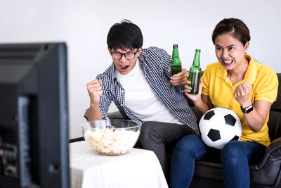 Friends with clenched fist watching soccer on tv