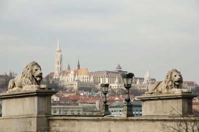 Statue in city against sky