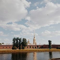 View of building by river against cloudy sky