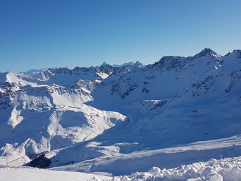 Scenic view of snowcapped mountains against clear blue sky