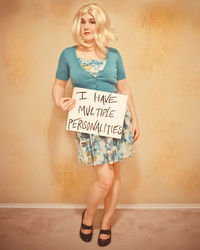 Portrait of woman holding paper with text while standing against wall