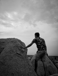 Man on rock against sky
