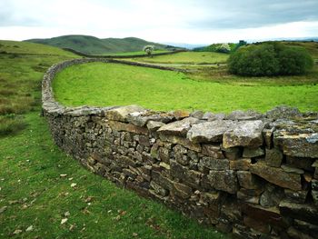 Stone wall on field against sky