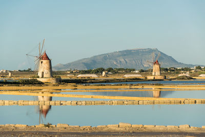 Traditional windmills by lake against clear sky