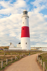 Full length of boy standing by lighthouse against sky