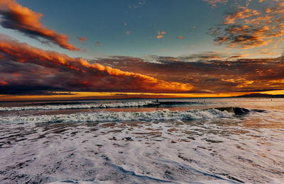 Scenic view of sea against dramatic sky during sunset