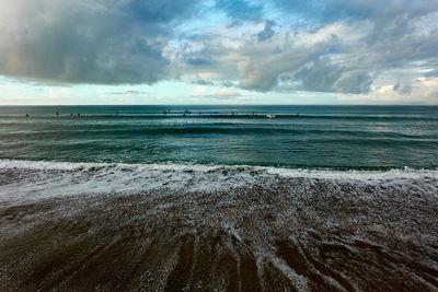 Scenic view of sea against sky with surfers