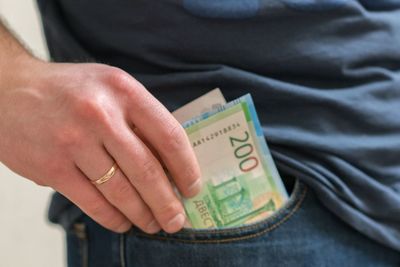 Midsection of man removing paper currencies from pocket