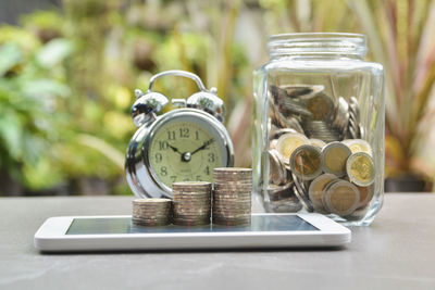 Close-up of alarm clock and coins on table