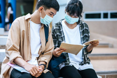 Friends sitting on a man holding paper outdoors